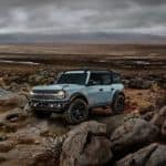 A popular Ford SUV, a pale blue 2021 Ford Bronco 4-door Badlands, is parked on some rocks.