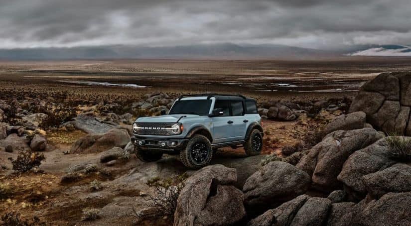 A popular Ford SUV, a pale blue 2021 Ford Bronco 4-door Badlands, is parked on some rocks.