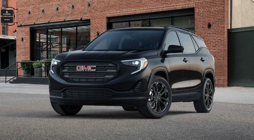 A black 2021 GMC Terrain is parked in front of a gallery angled left.