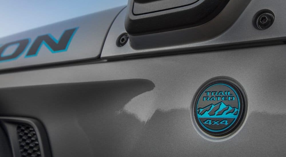 A close up of the blue "Trail Rated 4x4" badge is shown on a grey 2021 Jeep Wrangler 4Xe Rubicon.