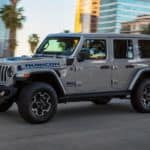 A grey 2021 Jeep Wrangler Rubicon 4Xe is driving down the road after leaving the Jeep dealership.