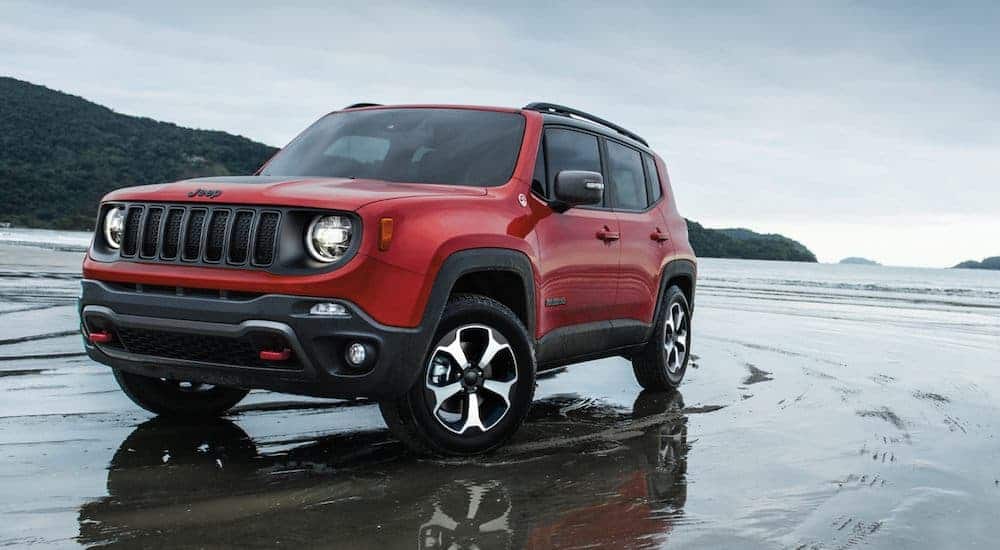 A red and black 2021 Jeep Renegade is parked on a beach in the wet sand.