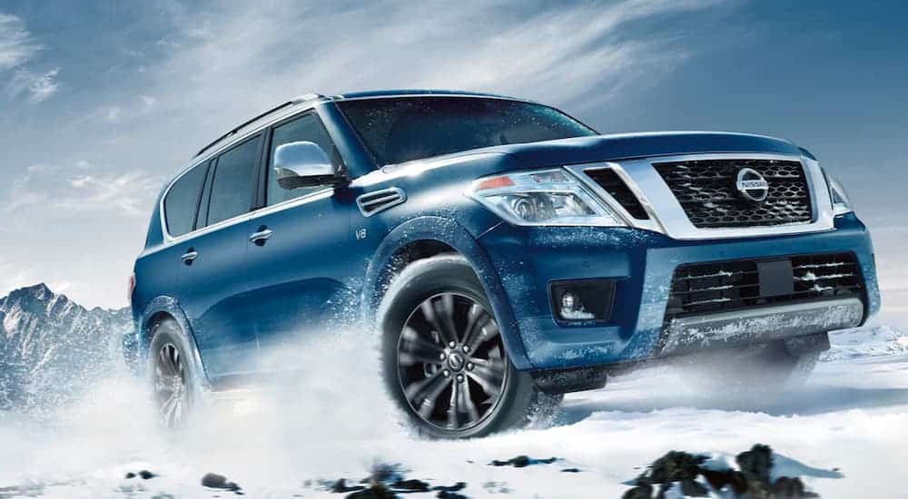 A popular Nissan SUV, a blue 2020 Nissan Armada is driving through the snow.