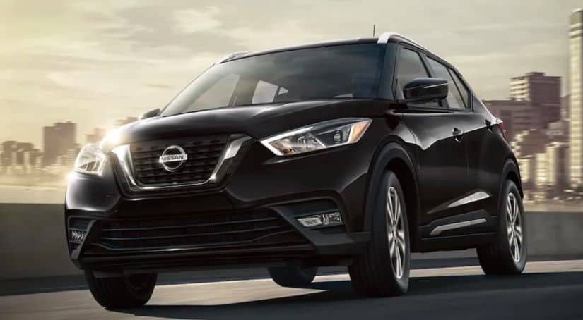 A black 2020 Nissan Kicks is driving away from the city.