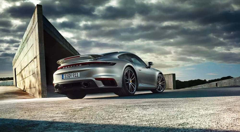 A silver 2021 Porsche 911 Turbo is shown from the rear near a concrete structure.