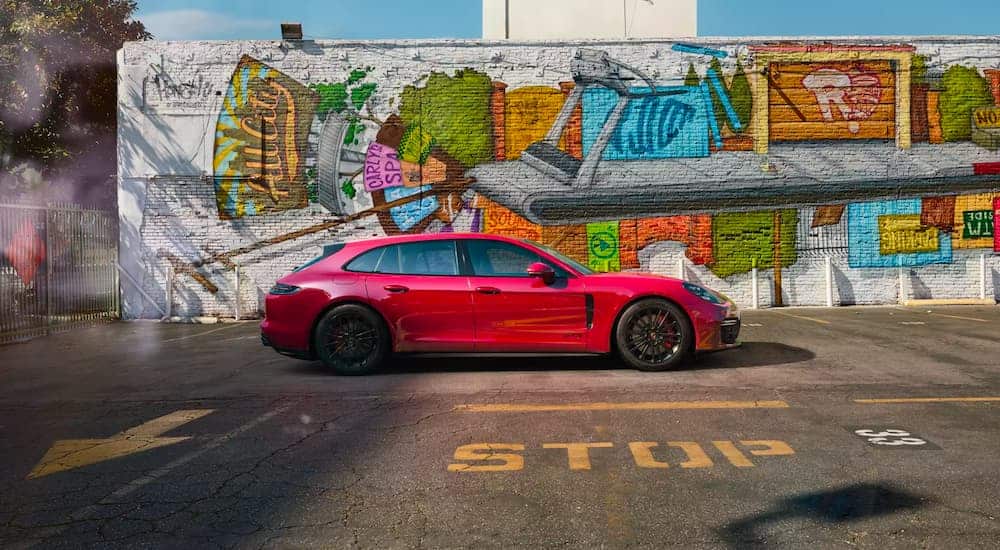 A red 2021 Porsche Panamera GTS is shown in profile with a mural in the background.