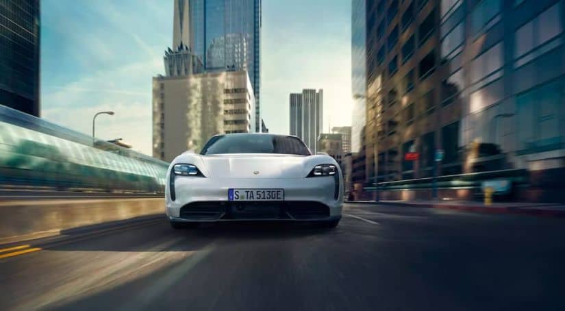 A white 2021 Porsche Taycan 4S is shown from the front driving through the city.
