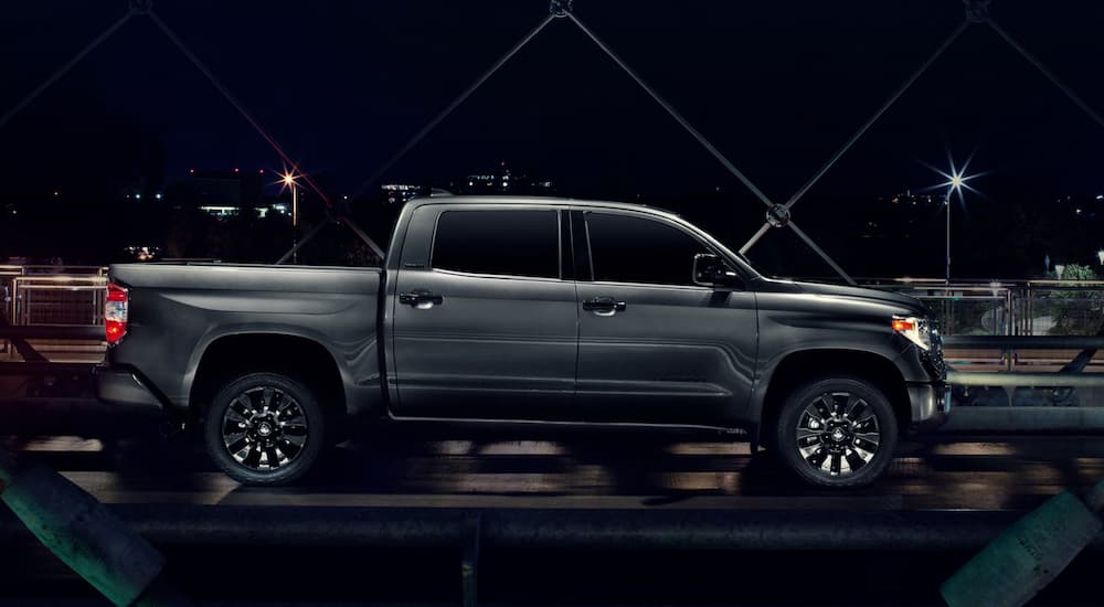 A grey 2021 Toyota Tundra is shown from the side on an urban bridge at night.