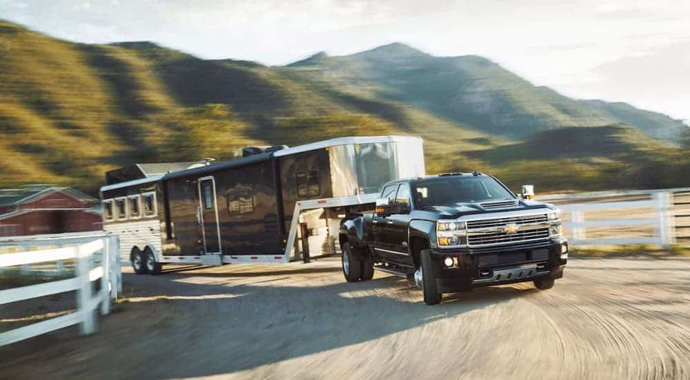 A black 2017 Chevy Silverado 3500HD is towing a large horse trailer after leaving a used Chevy diesel truck dealer.