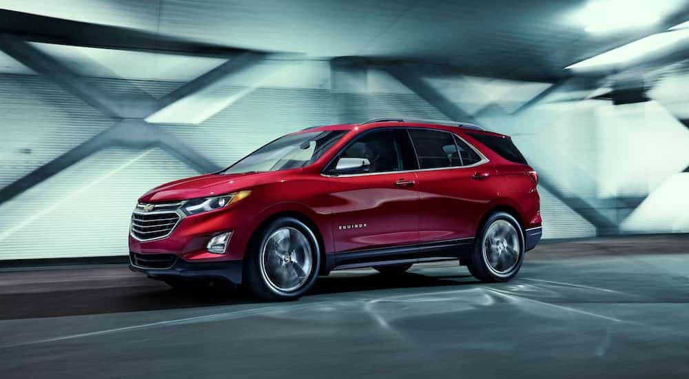 A red used 2018 used Chevy Equinox is shown in profile driving down a tunnel.