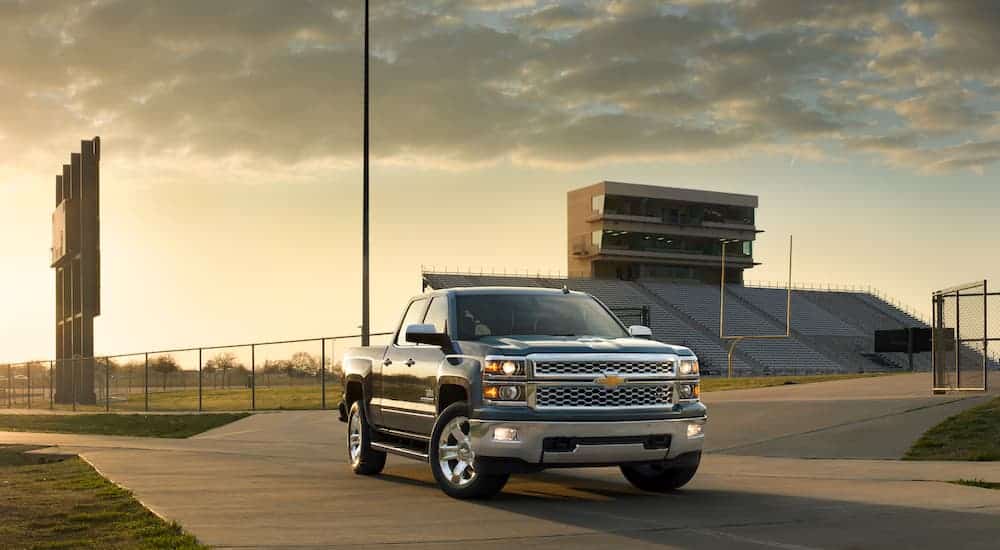 A black 2014 used Chevy Silverado 1500 LTZ Texas Edition is parked with a football field in the background.