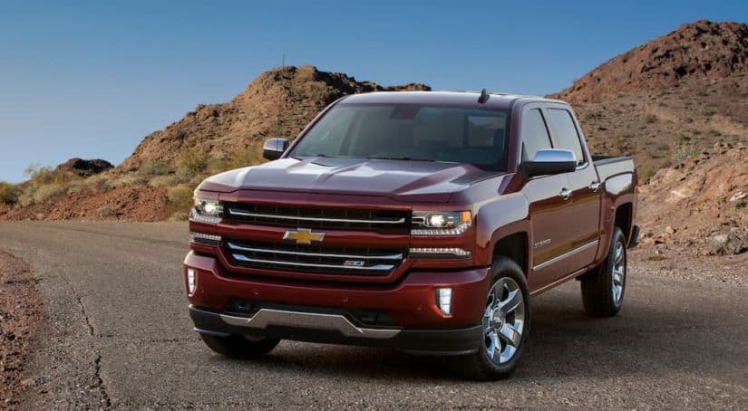 A red 2017 used Chevy Silverado 1500 Z71 is parked in the desert with hills in the background.