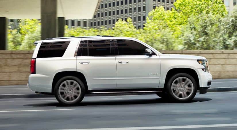 A white 2020 used Chevy Tahoe is shown from the side while driving on a city street.