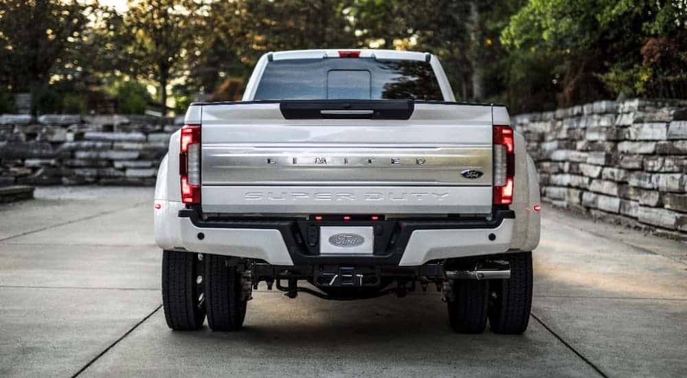A white 2018 Ford F-350 Limited diesel is shown from the rear in front of a stone wall.