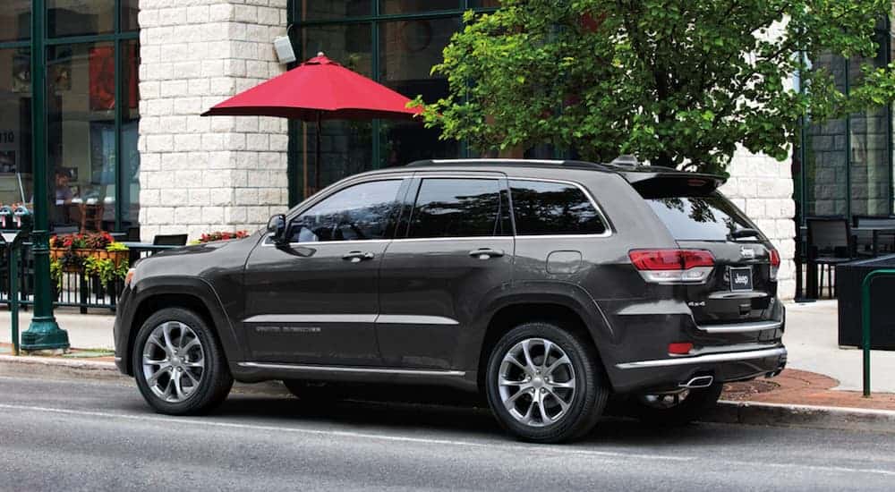 A grey 2020 Used Jeep Grand Cherokee Summit is parked on a city street.