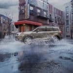 A tan 2017 used Subaru Forester is driving through the city in the rain.