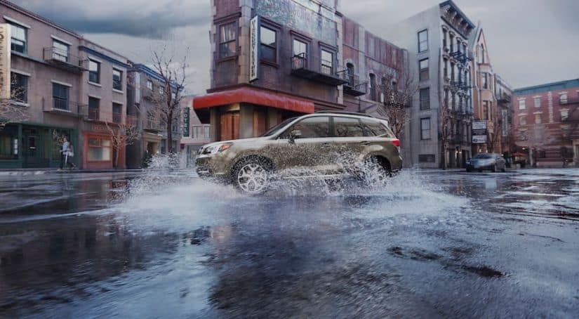 A tan 2017 used Subaru Forester is driving through the city in the rain.