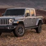 A grey 2020 used Jeep Gladiator is parked off-road at sunset with desert mountain views.
