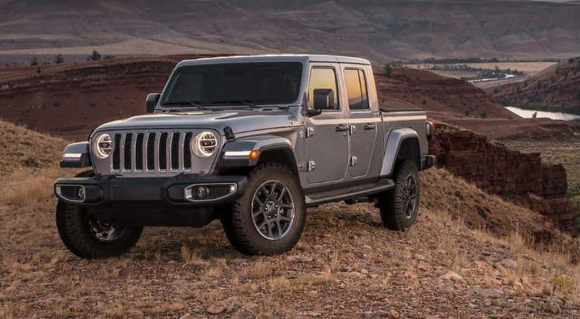 A grey 2020 used Jeep Gladiator is parked off-road at sunset with desert mountain views.