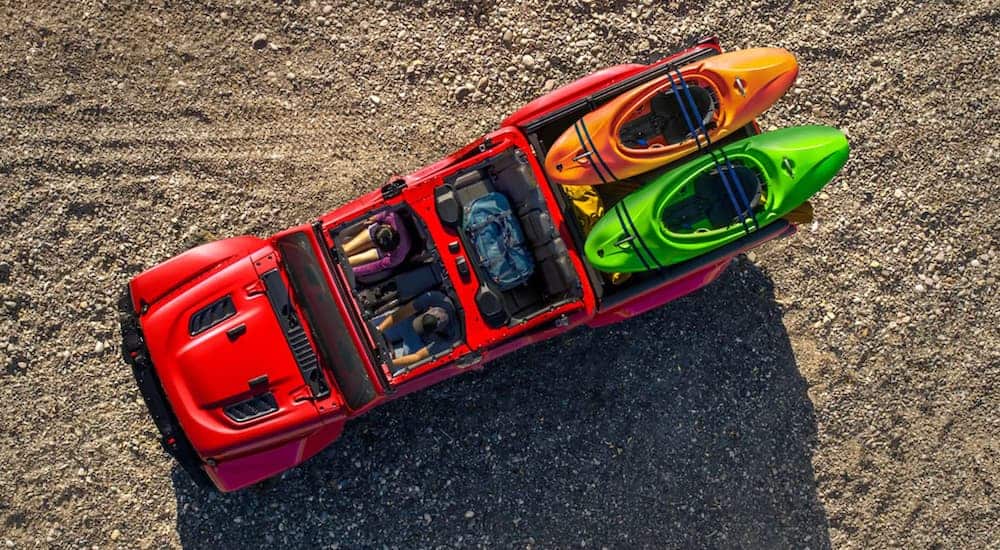 A red 2020 used Jeep Gladiator Rubicon is shown from above with the doors and roof off and kayaks in the bed.