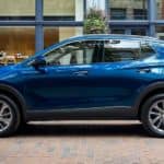 A blue 2021 Buick Encore GX is shown from the side in front of a glass building.