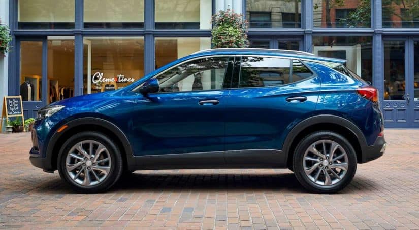 A blue 2021 Buick Encore GX is shown from the side in front of a glass building.