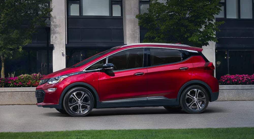 A red 2021 Chevy Bolt is shown in profile parked in front of flower planters.