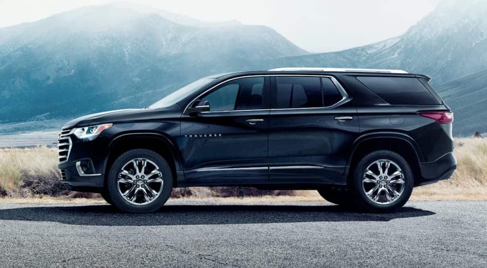 A black 2021 Chevy Traverse High Country is shown from the side on a road in front of misty mountains.