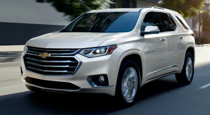 A white 2021 Chevy Traverse is driving on a city street.