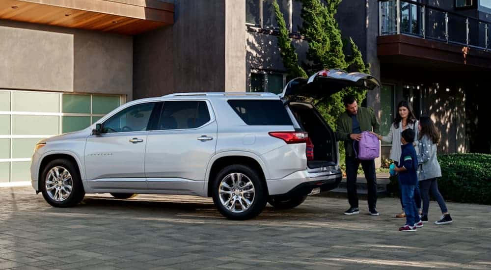 A family is loading up the back of a white 2021 Chevy Traverse in front of a garage.