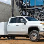 A popular 2021 commercial vehicle, a white Silverado Chassis Cab, is parked in front of a concrete building at a jobsite.