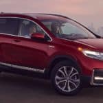 A red 2021 Honda CR-V Hybrid is parked on the dirt overlooking a city after winning the 2021 Honda CR-V vs 2021 Kia Seltos comparison.