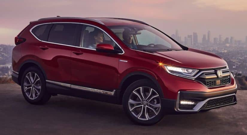 A red 2021 Honda CR-V Hybrid is parked on the dirt overlooking a city after winning the 2021 Honda CR-V vs 2021 Kia Seltos comparison.