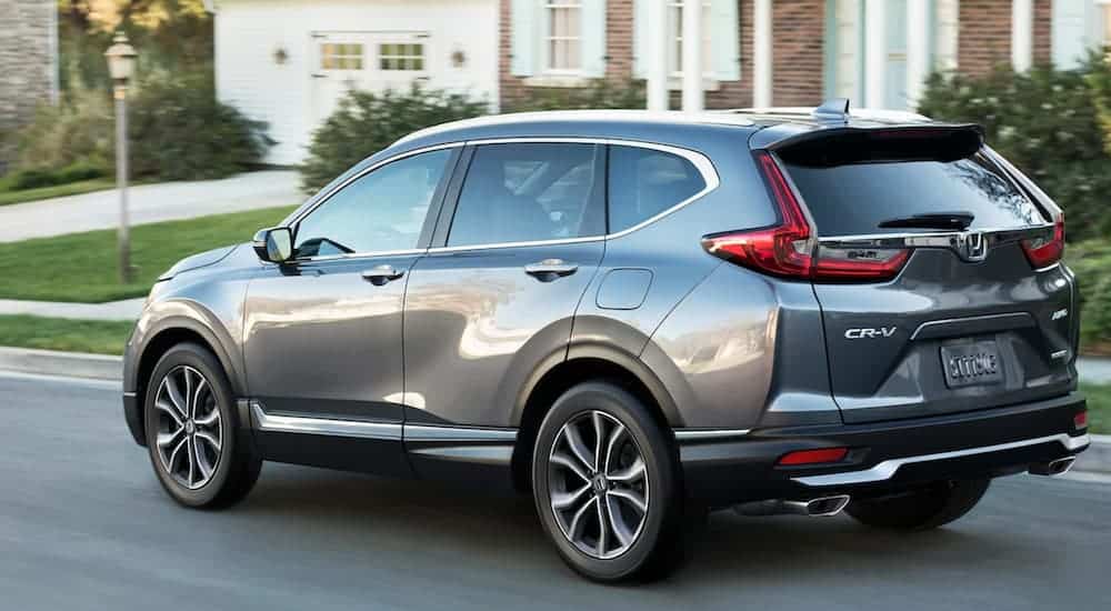 A dark gray 2021 Honda CR-V is shown from the side driving down a suburban street.