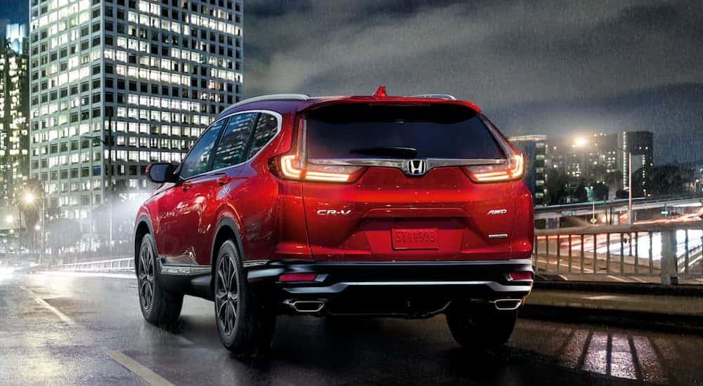 A red 2021 Honda CR-V Touring is shown from the rear on a city street.