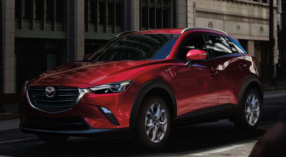 A red 2021 Mazda CX-3 is shown parked in the city, angled right.
