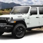 A white 2021 Jeep Wrangler Unlimited Willys is angled left in front of a mountain.