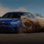 A blue 2021 Kia Forte is driving through the dirt after winning the 2021 Kia Forte vs 2021 Honda Civic comparison.
