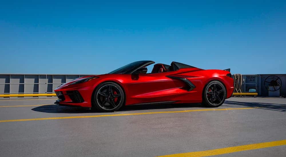 A red 2021 Chevy Corvette Stingray convertible is parked against a clear blue sky.