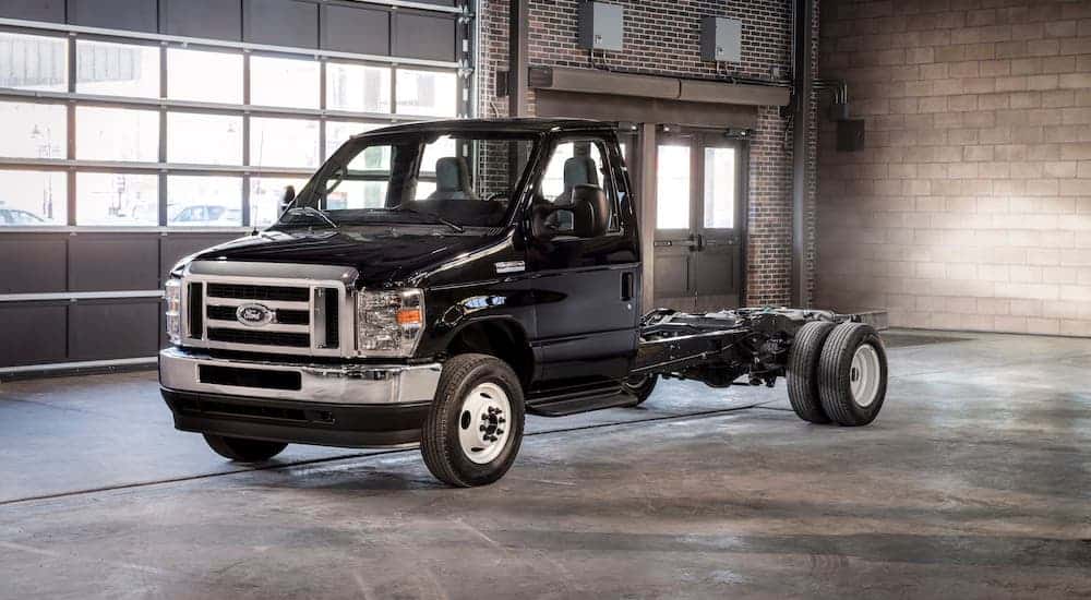 A black 2021 Ford E-Series cutaway van is parked in a brick garage.