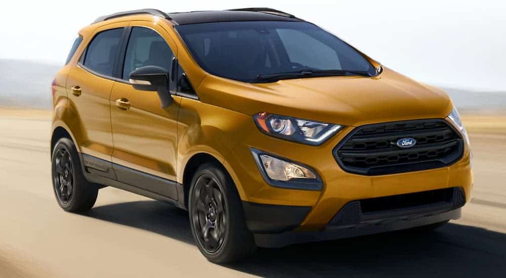 A gold 2021 Ford EcoSport is driving on a bright road with a blurred background.