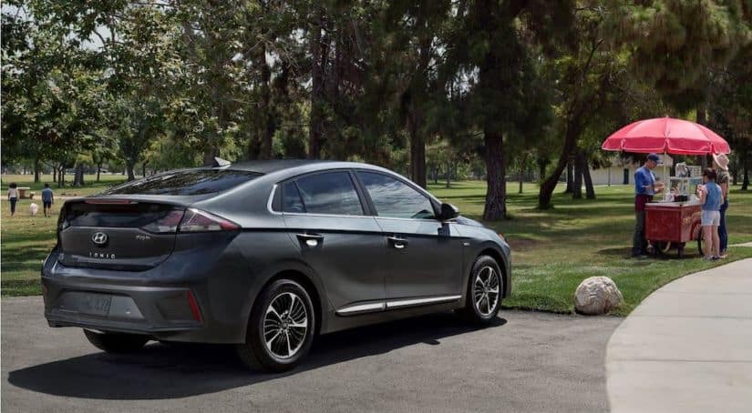 A gray 2021 Hyundai Ioniq Plug In is parked at a park in front of a snow-cone stand.