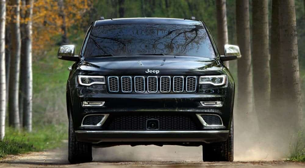 A black 2019 Jeep Grand Cherokee is shown from the front on a dirt road after leaving a used Jeep dealer.