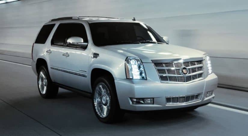 A silver 2014 Cadillac Escalade is driving in a tunnel.