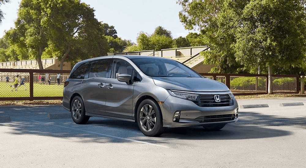 A gray 2020 Honda Odyssey is parked in front of a soccer field.