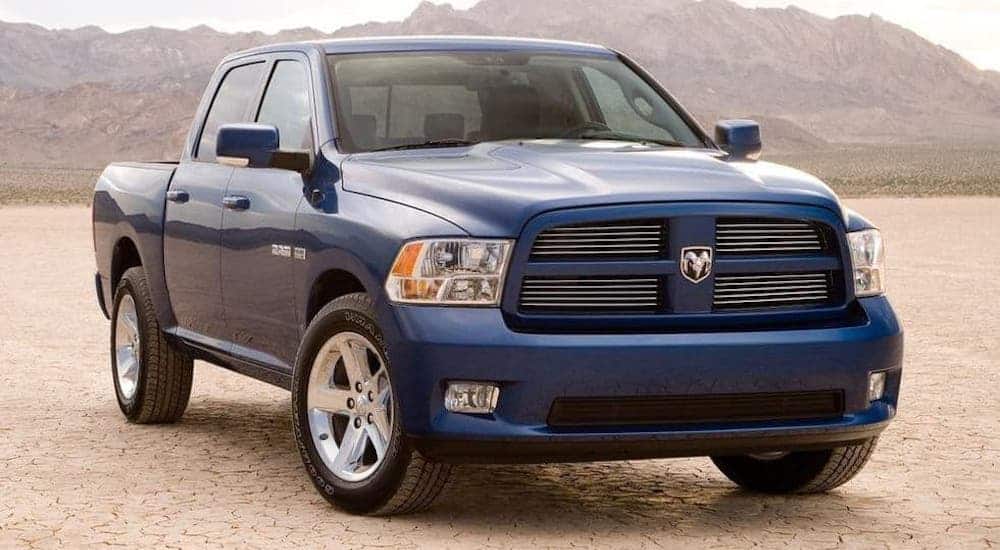 A blue 2009 used Ram 1500 is parked in a desert in front of distant mountains.
