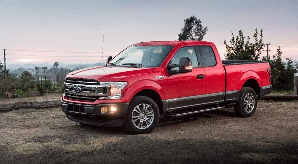 A red 2018 Ford F-150 is shown from the side parked in a dirt lot.