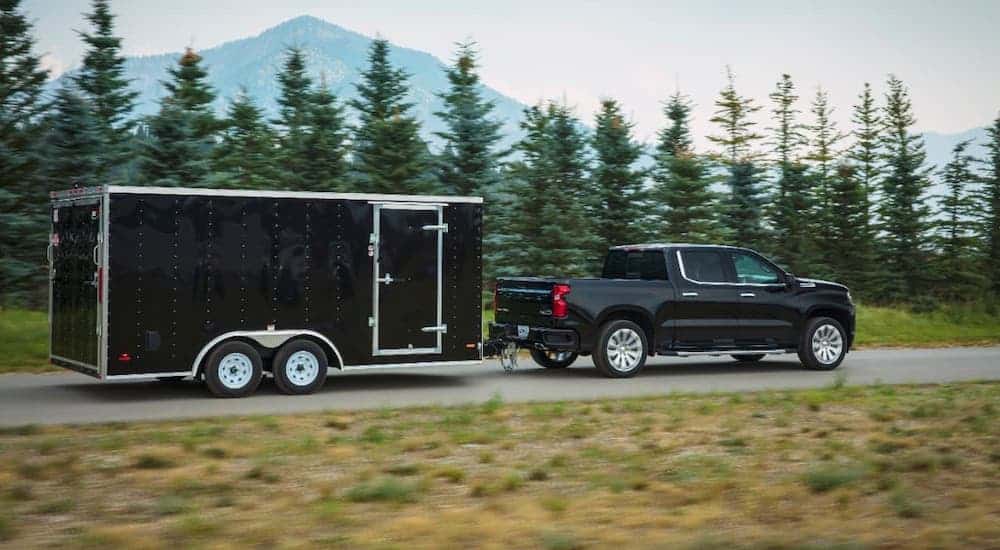 A black 2019 Chevy Silverado 1500 is shown from the side towing a black enclosed trailer.