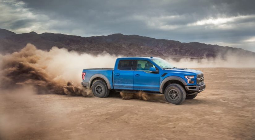A blue 2022 Ford F-150 is shown from the side off-roading in a desert after leaving a certified pre-owned F-150 dealer.