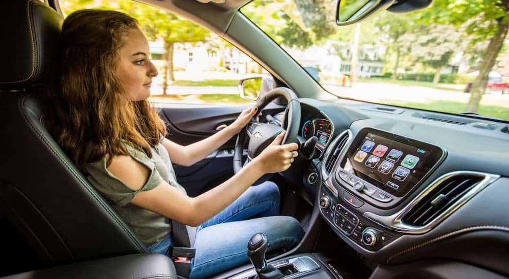 A teenager is shown from the passenger side driving a 2021 Chevy Equinox.